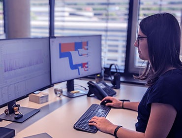 Mitarbeiterin vor Monitor mit Diagrammen